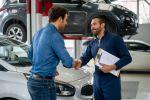 Un mecánico y su cliente se dan la mano después de conversar sobre el arreglo de su carro