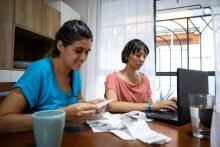 dos mujeres mirando recibos mientras hacen su presupuesto mensual