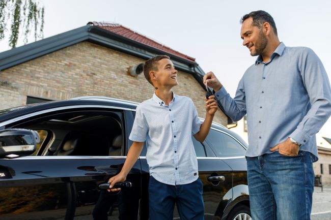 Un niño y su padre se suben a su coche.