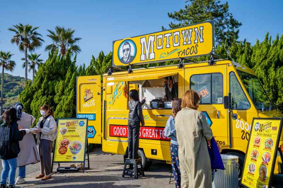 Customers ordering food from a yellow taco truck