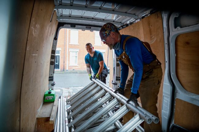 Dos trabajadores poniendo una escalera en su camion de trabajo