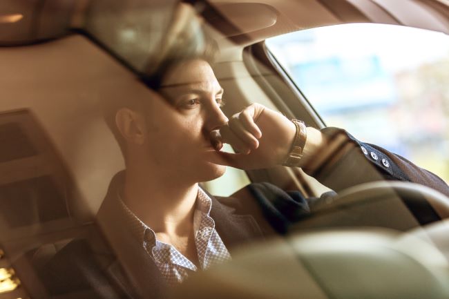 un hombre que parece molesto mientras esta sentado en su auto