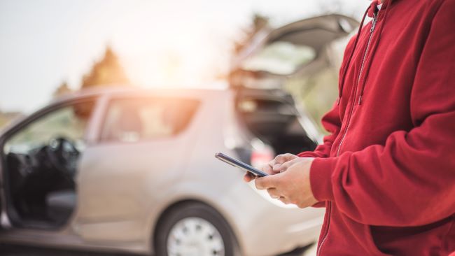  un senor usa su celular para obtener estimados para la aseguranza de su carro