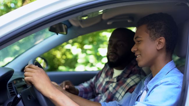 un hombre mostrando a un nino como conducir un automovil