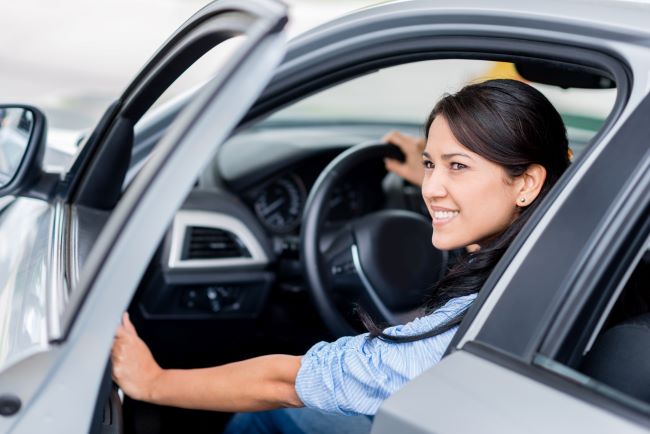 una dama a punto de salir de su auto mirando algo